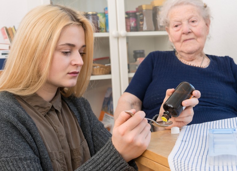 Eine junge Frau pflegt eine ältere Frau indem sie Medizin portioniert. Eine junge Frau pflegt eine ältere Frau indem sie Medizin portioniert.