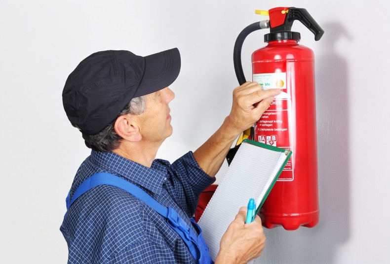 Eine Person prüft den Feuerlöscher. 